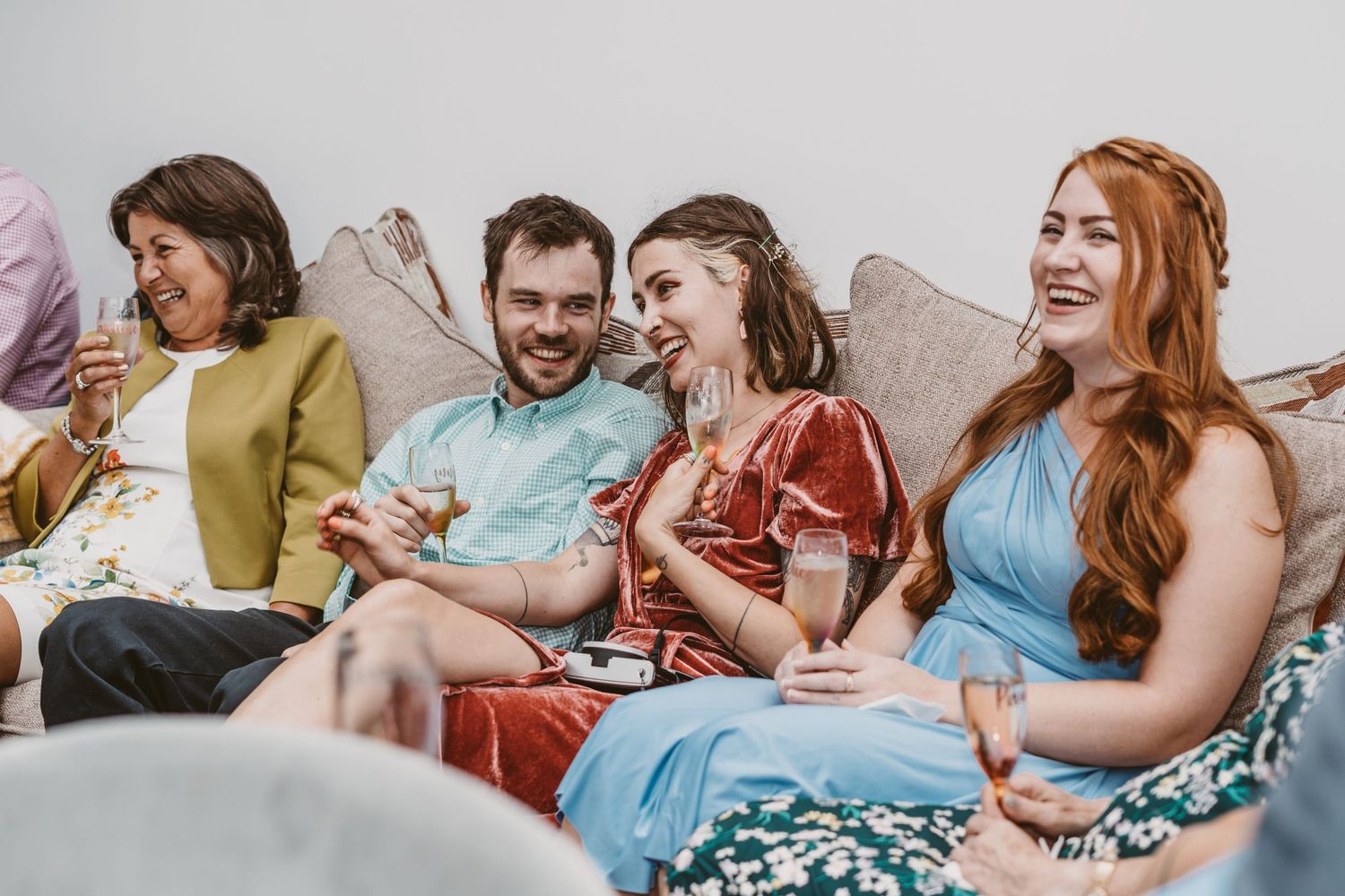 Group of friends laugh together while relaxing on couch during casual gathering.