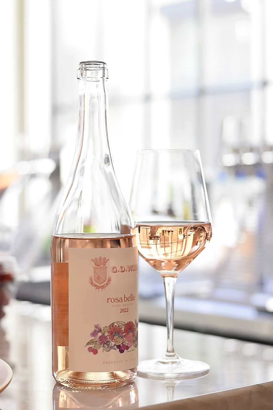 Bottle and glass of rose wine in bright natural lighting.