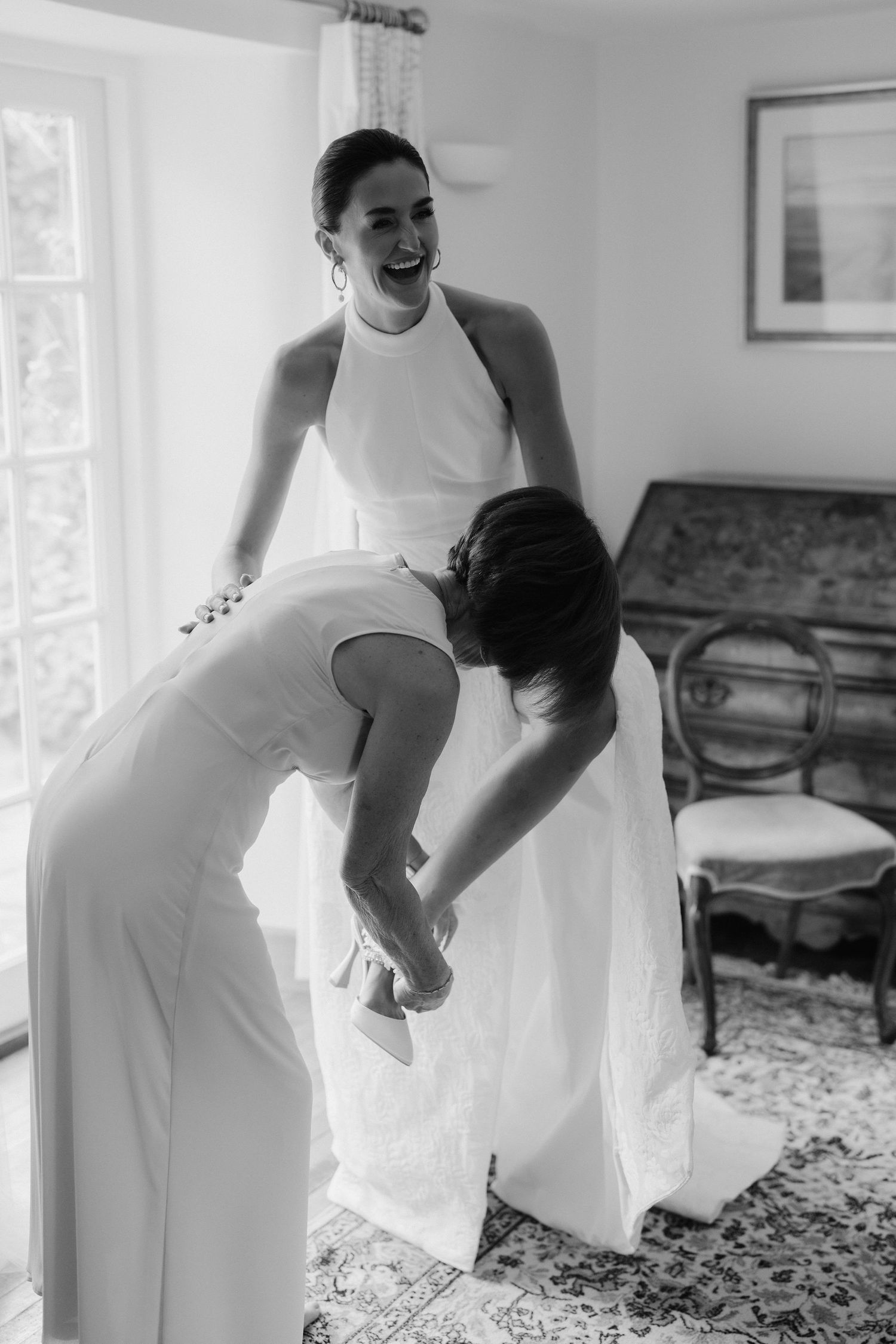 brides mum helping bride with her shoes as bride laughs