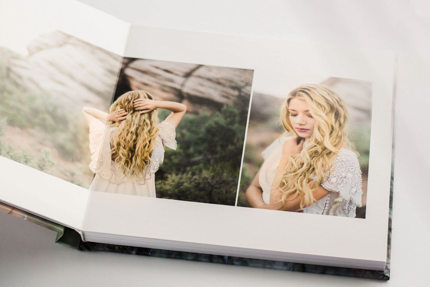 A photobook lies open to display artistically styled portrait photographs on glossy pages.