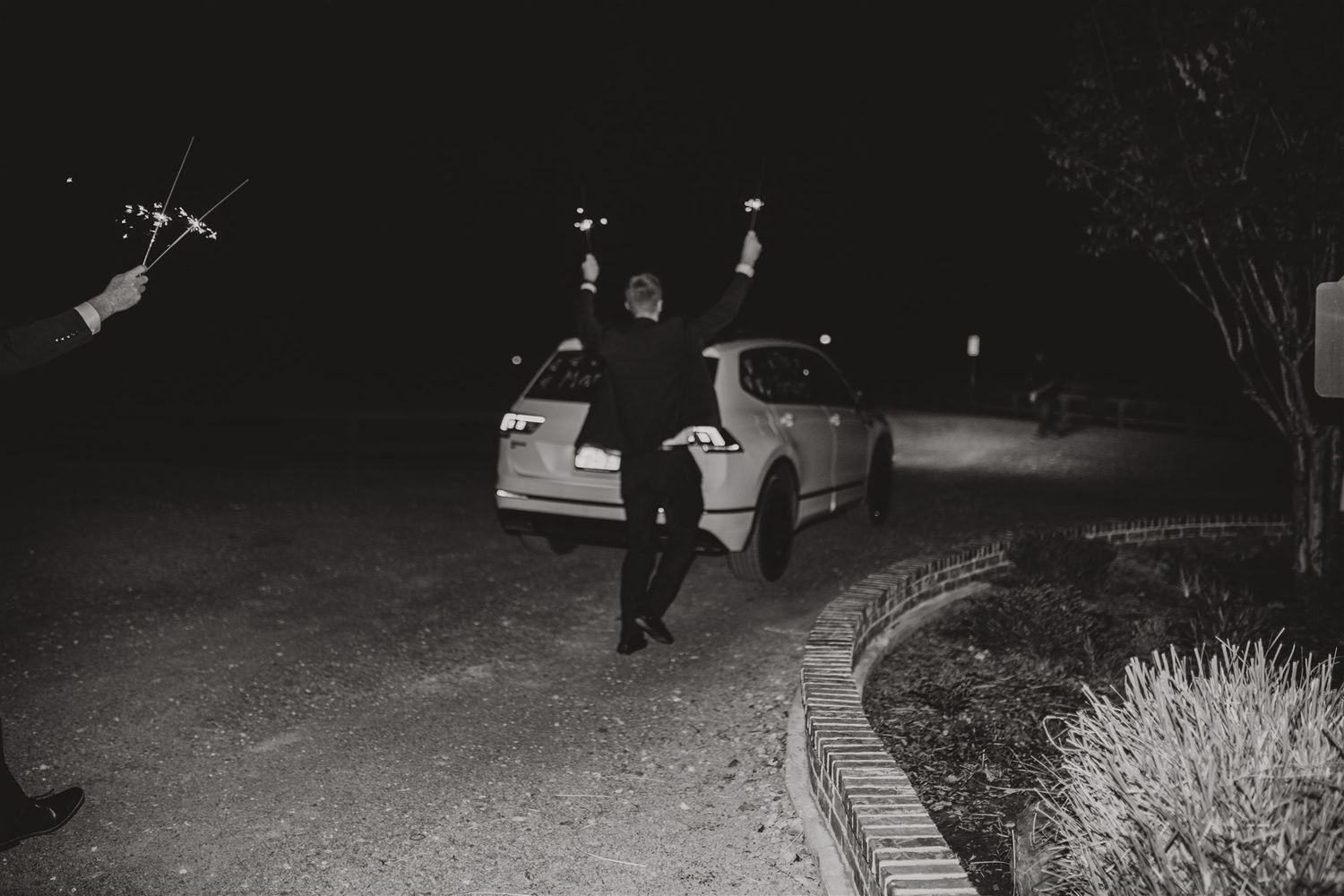 Night shot of wedding guests and car during nighttime departure.