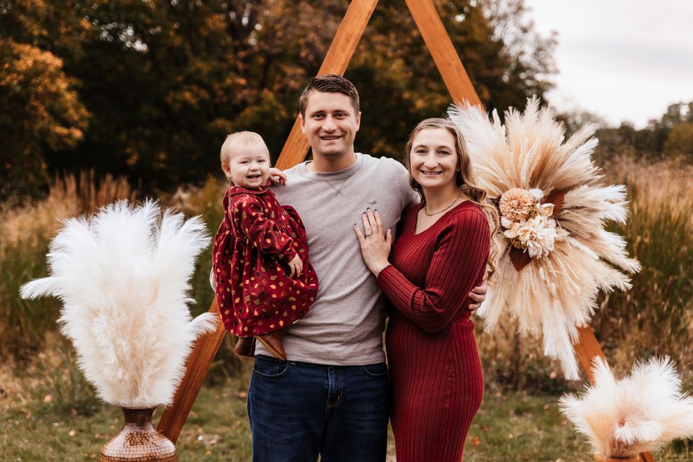 Outdoor family photo session with decorative pampas grass arrangements at sunset.