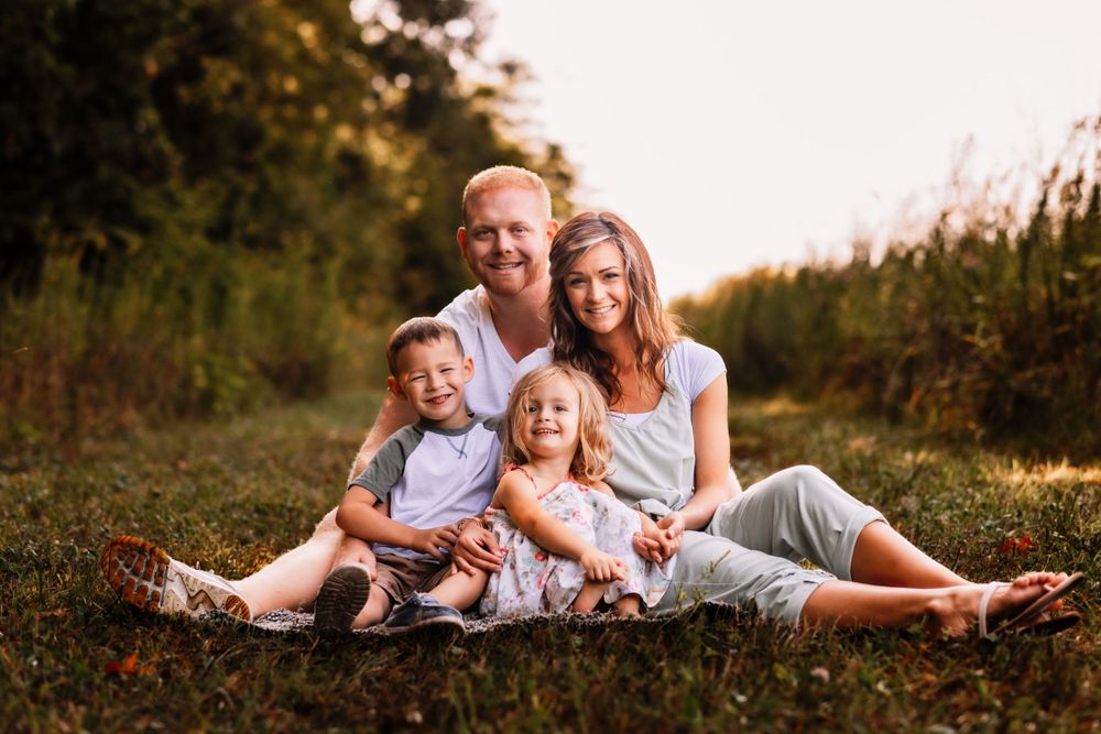 Family lying together on grass during golden hour photography session.
