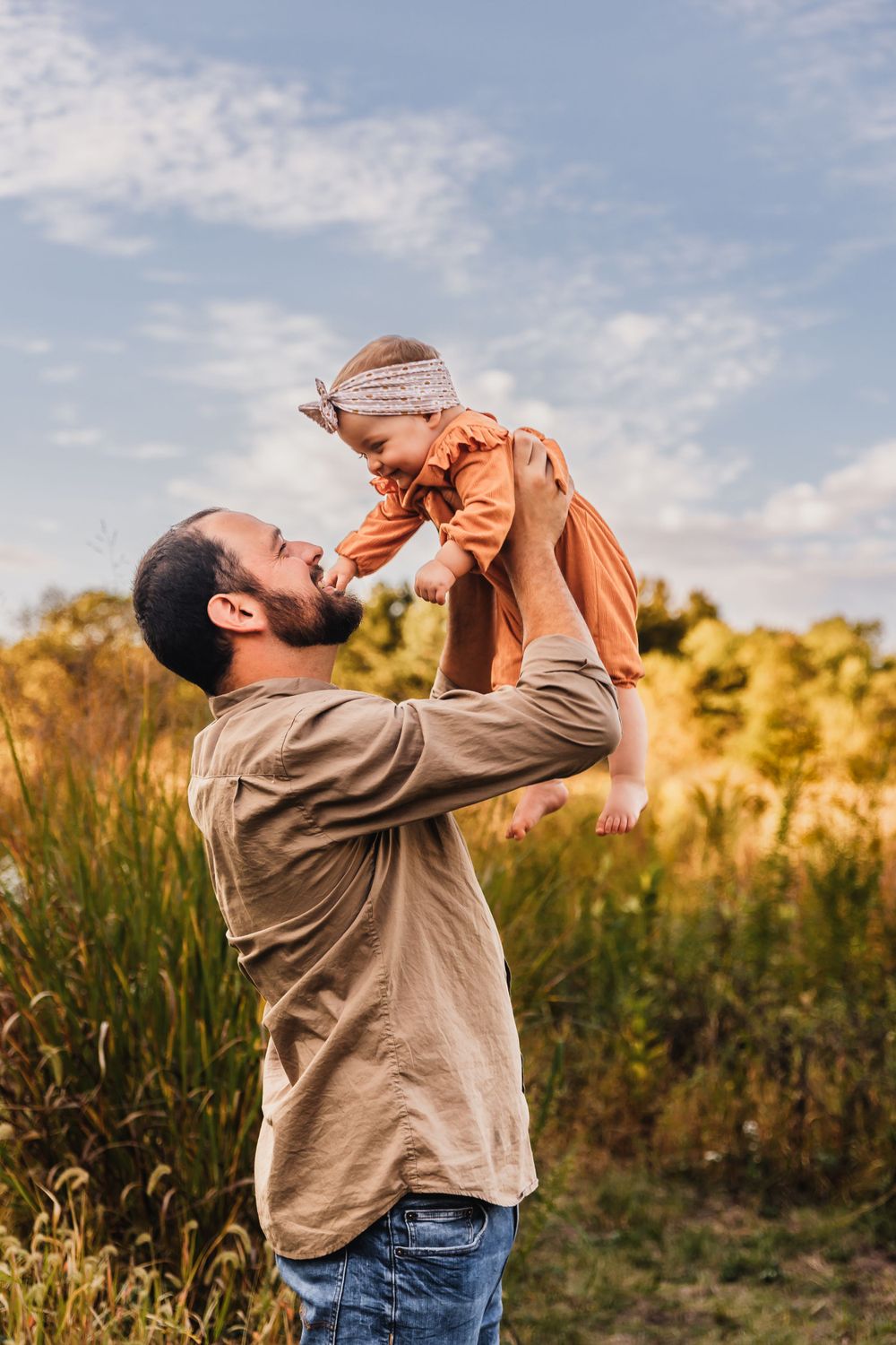 A playful moment captured at sunset in a field with tall grass and golden light.
