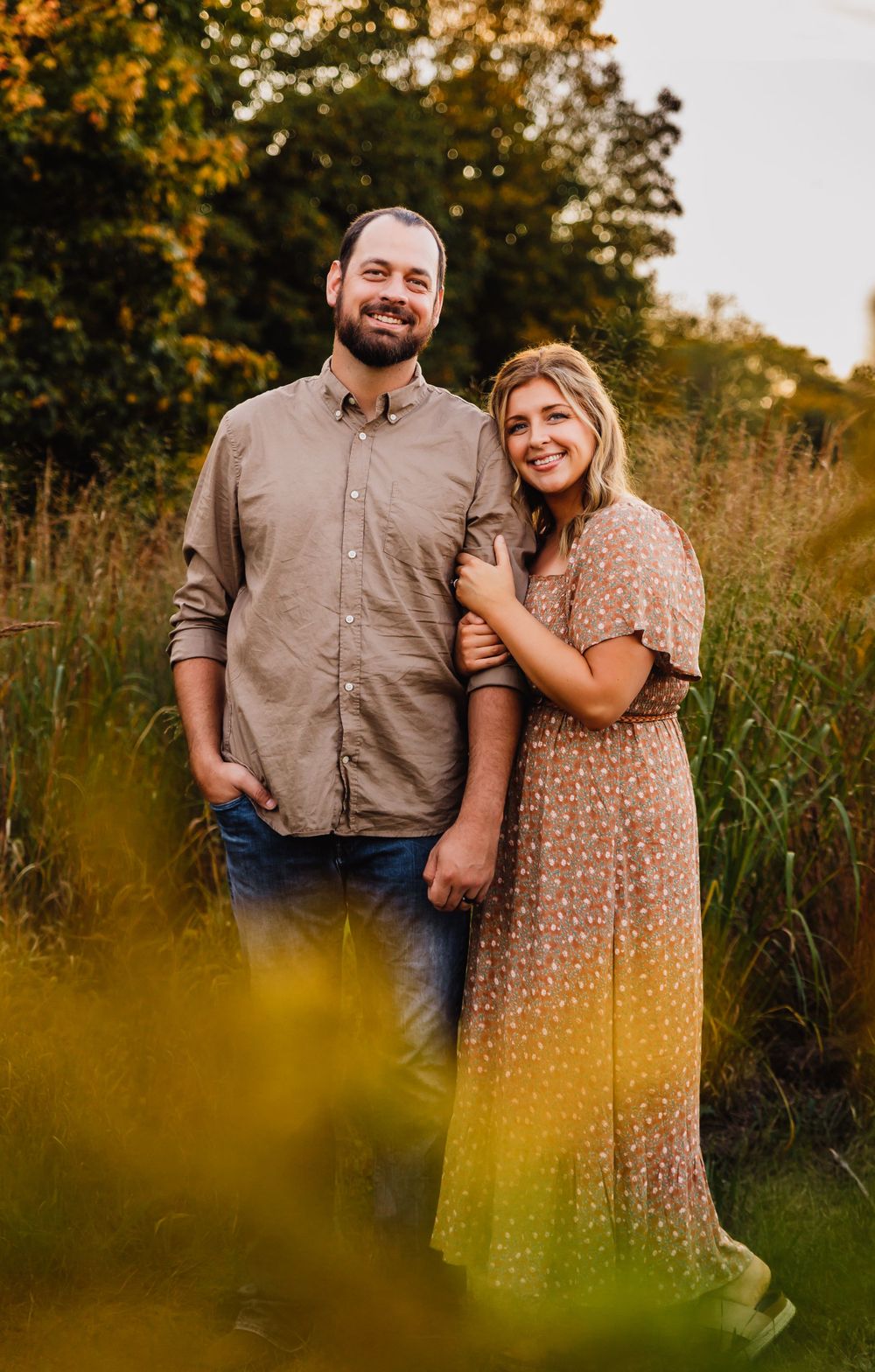 A romantic autumn photoshoot in a field with tall grass during golden hour.