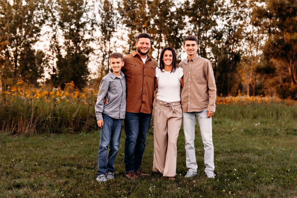 Outdoor family photoshoot in a golden field during sunset with autumn colors and natural lighting.