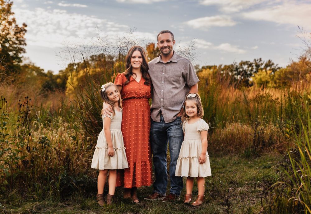 An autumn family portrait in a golden field at sunset.