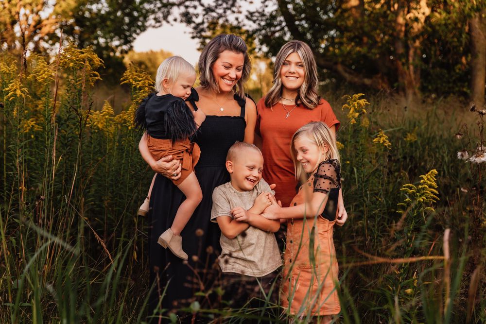 Group portrait in a rustic outdoor setting with warm fall colors and tall grass.