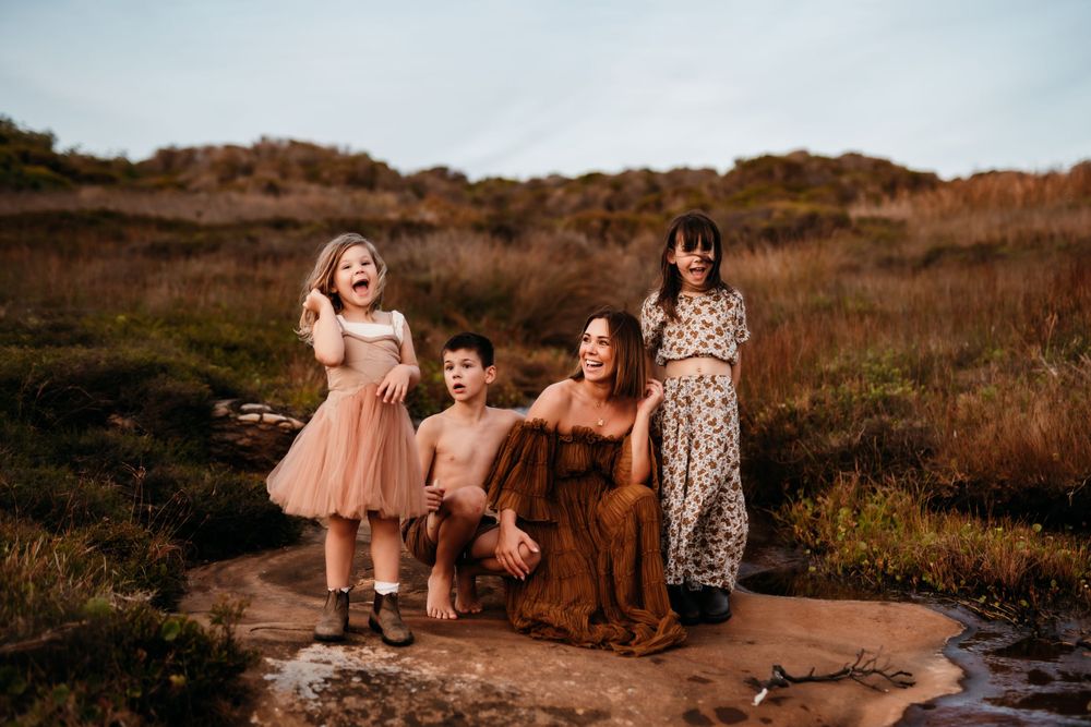 Mother and children laugh together in an earthy headland setting in Sydney