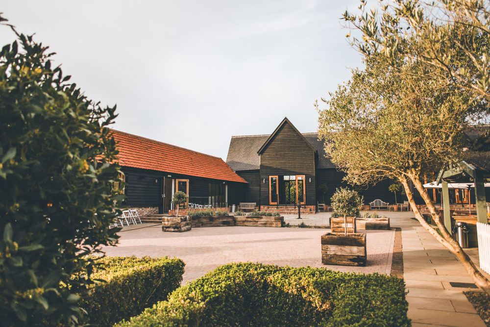 Rustic wedding venue buildings with orange roofs and manicured garden paths.