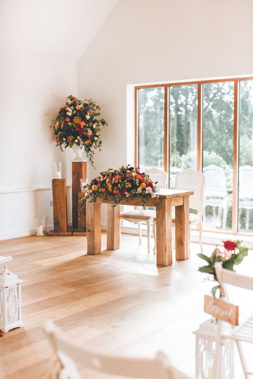 Elegant wedding ceremony venue with wooden beams and floral arrangements in natural light.