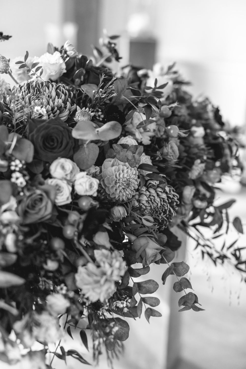 Black and white close-up of elegant wedding floral arrangement with roses and mixed blooms.