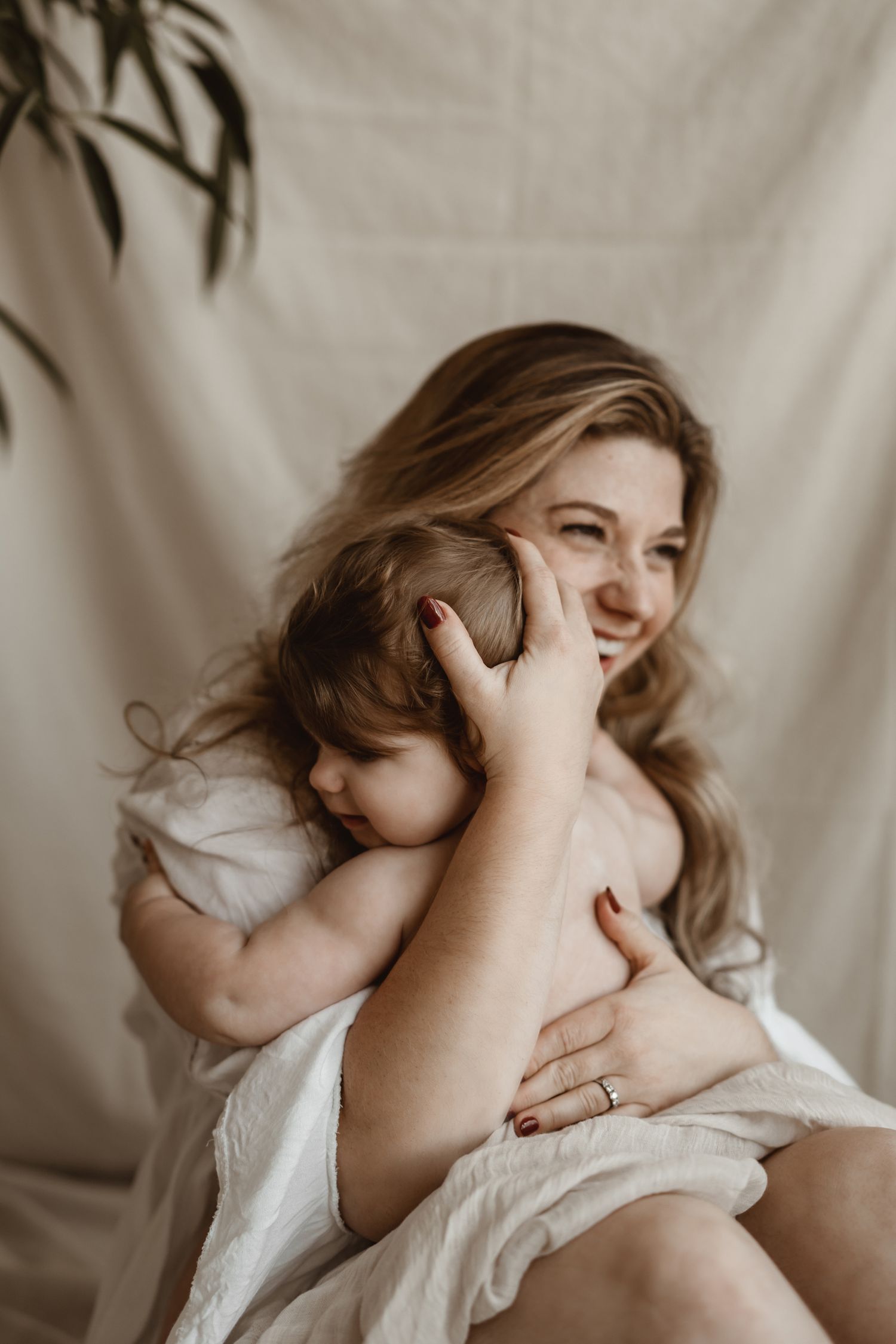 Joyful moment between parent and child in white clothing against neutral backdrop.