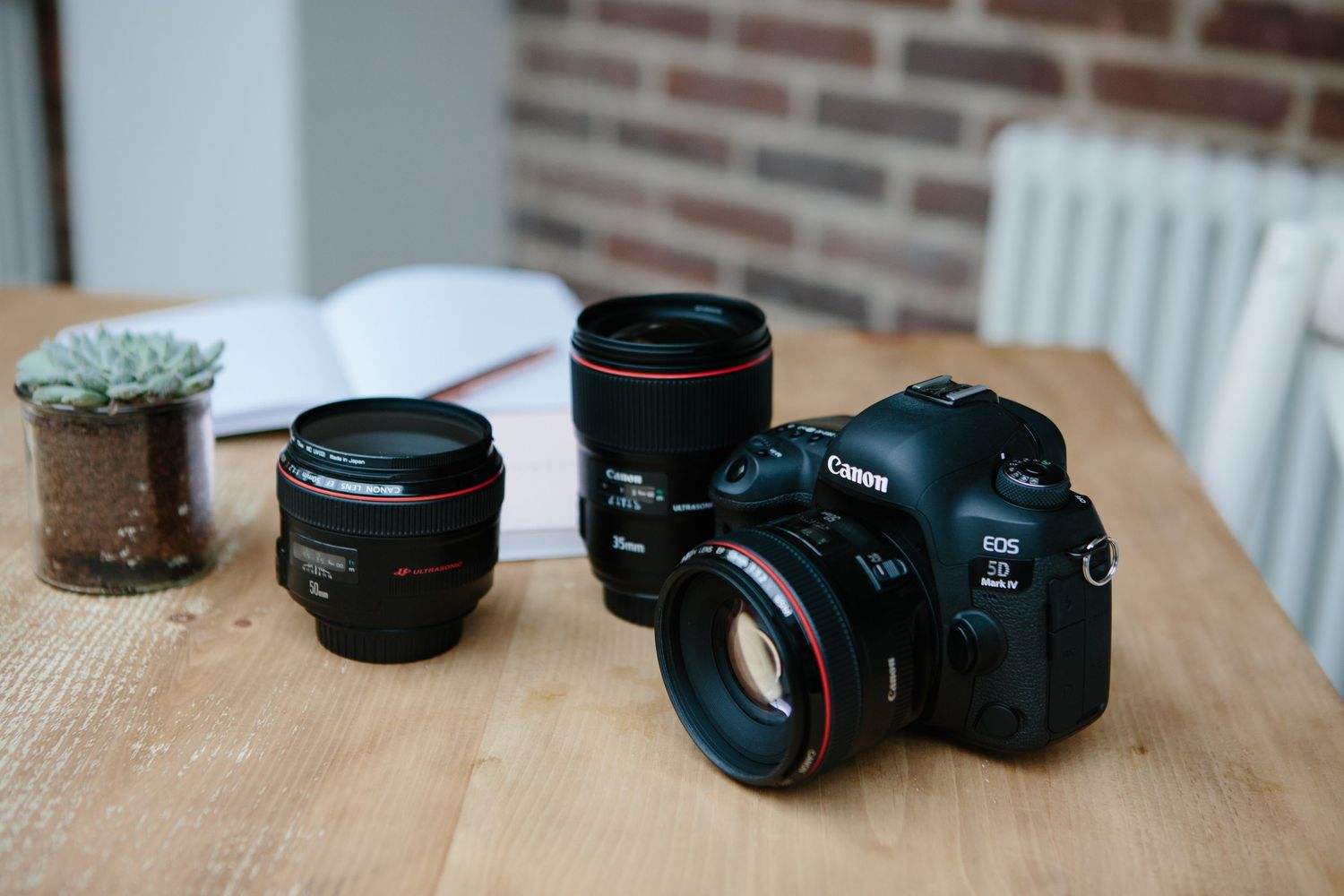 A professional camera setup with multiple lenses displayed on a wooden table surface.