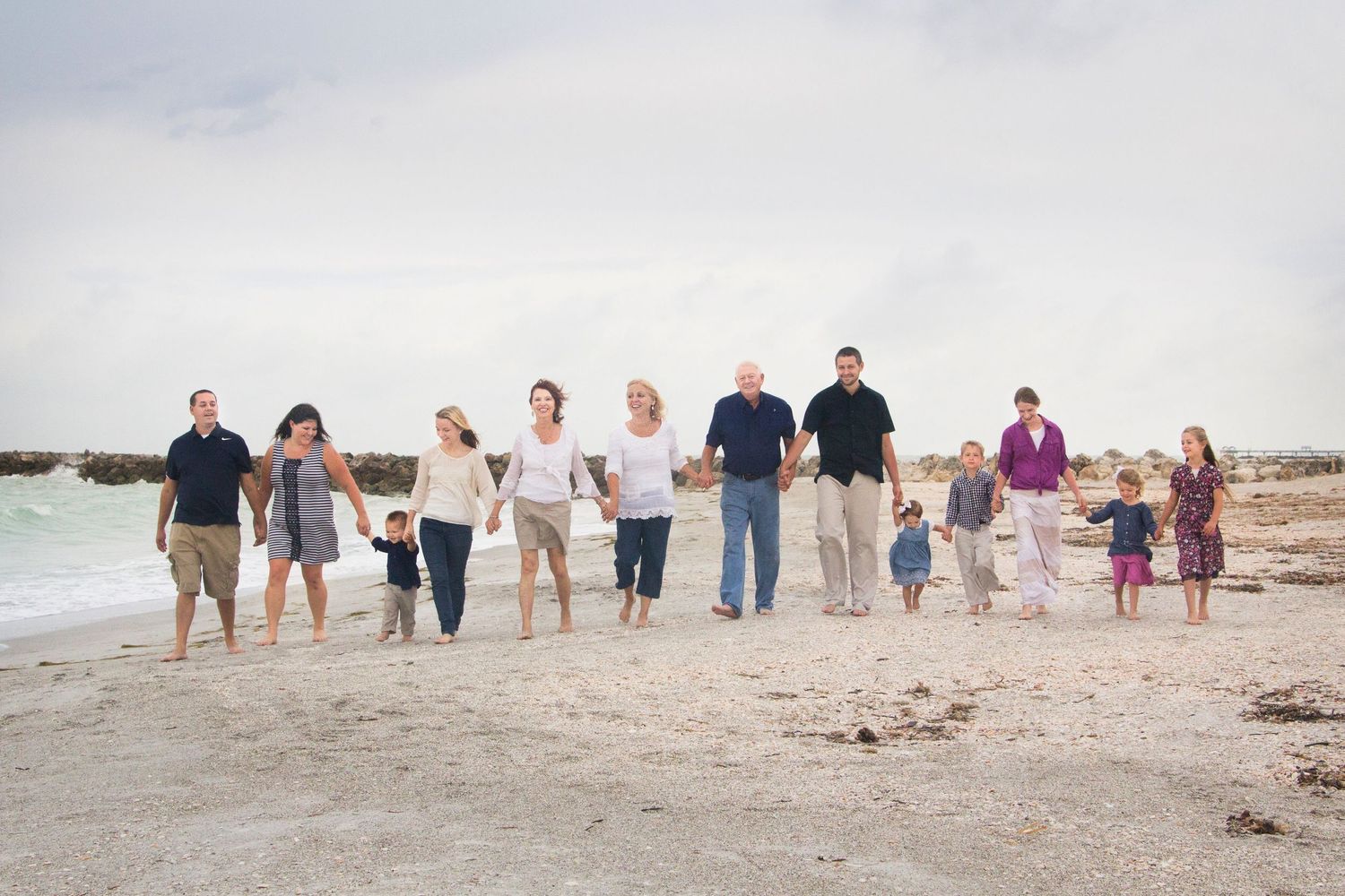 Large family all holding hands walking the beach along the coast line.