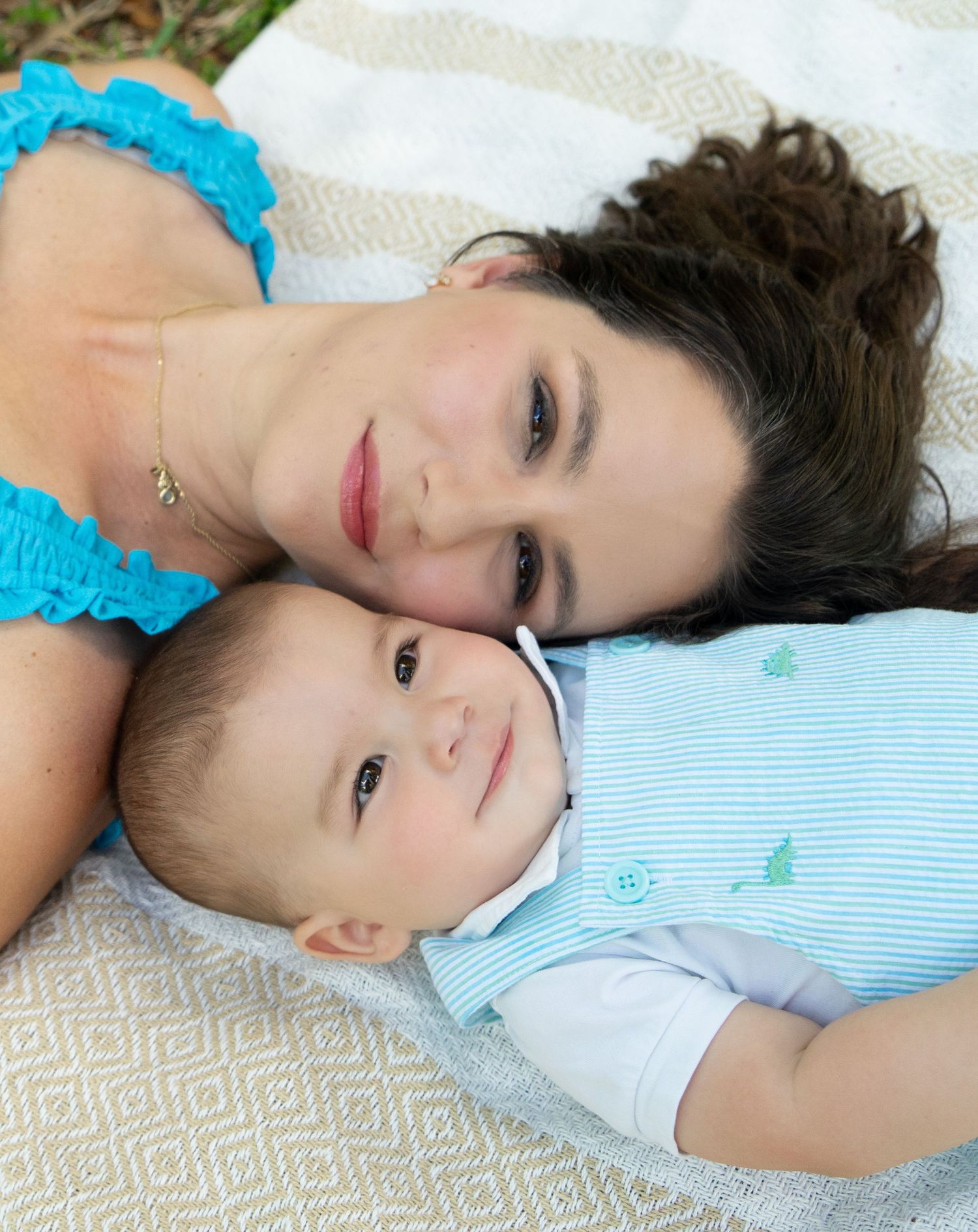 A tender moment captured between parent and baby lying together on a white blanket.