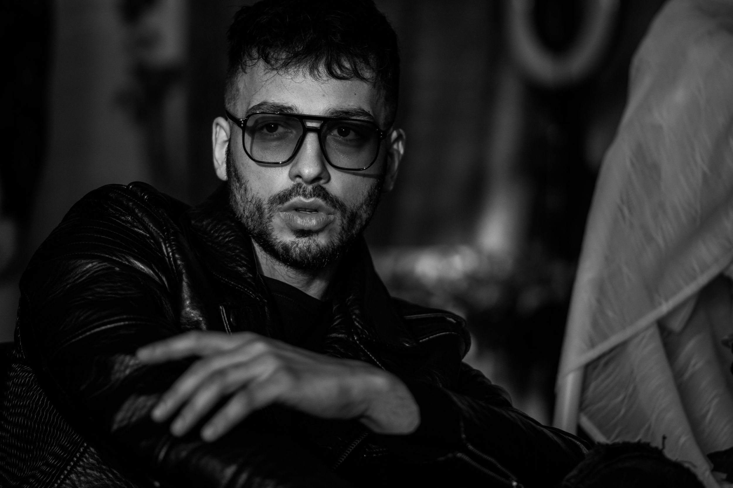 Artistic black and white portrait of a person wearing glasses in dramatic shadows.
