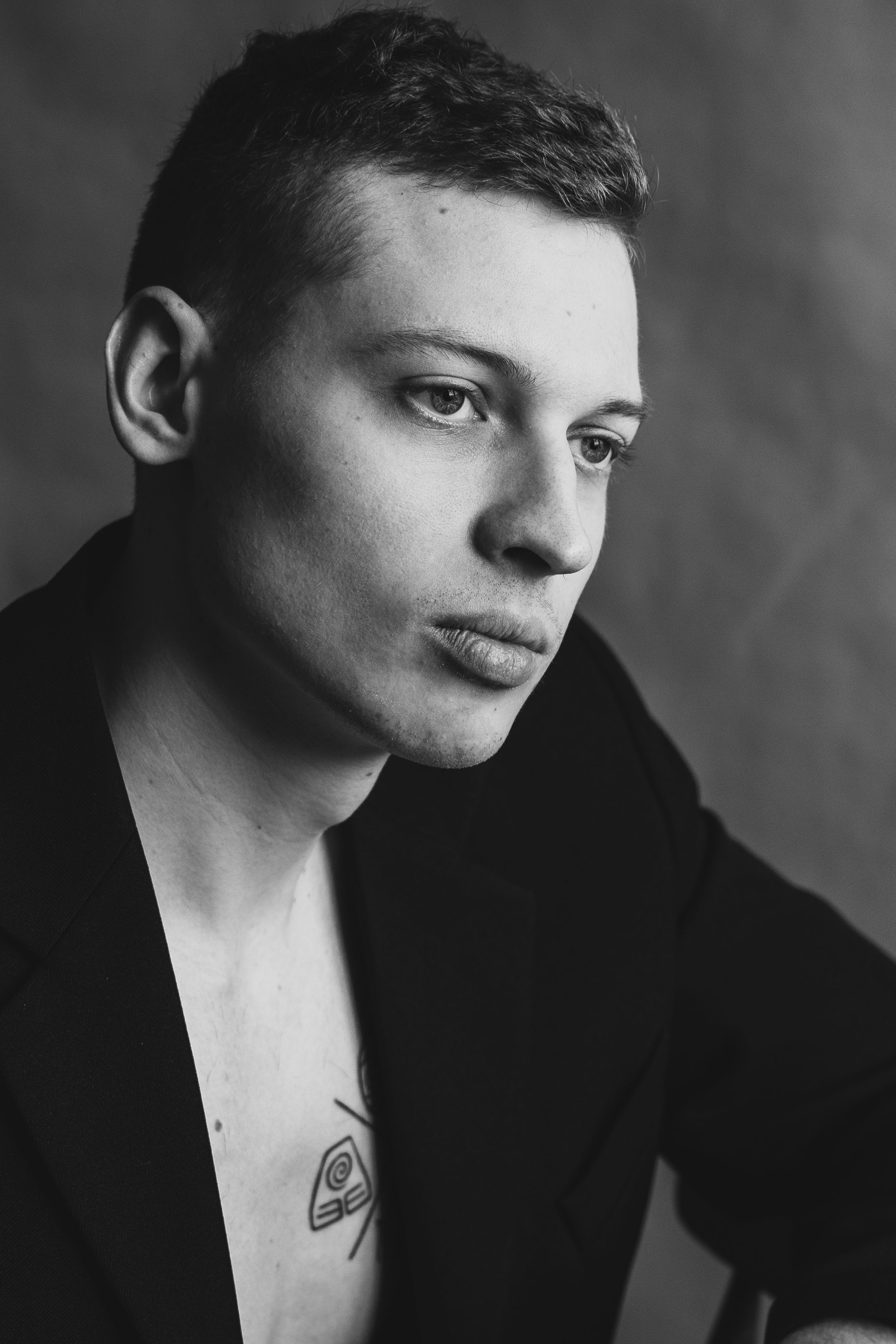 Dramatic black and white portrait showing tattoo detail.