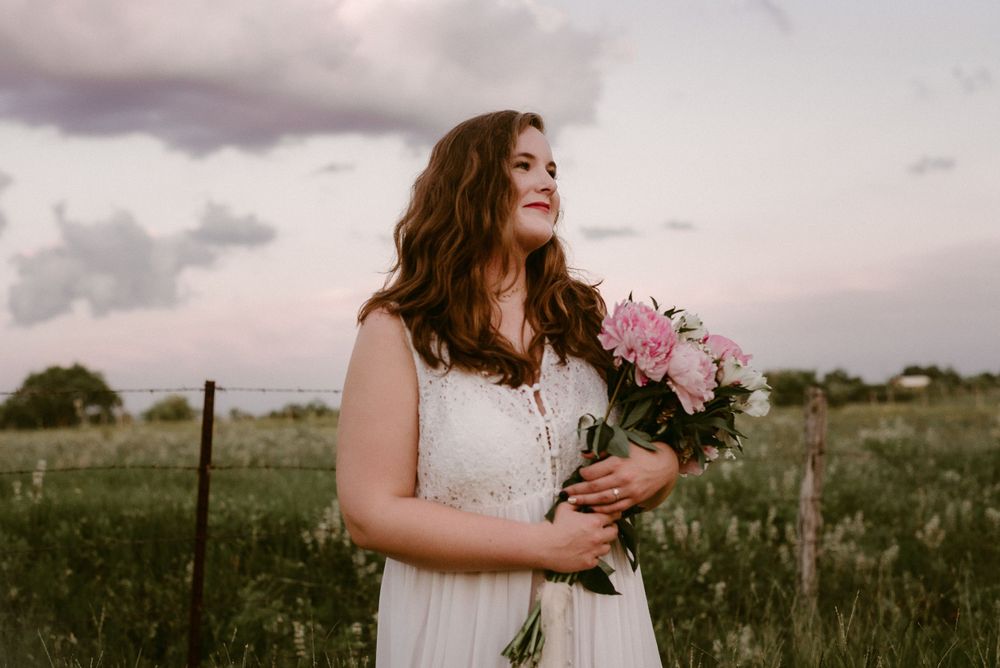 Dreamy portrait with pink flowers and flowing white dress in natural setting.