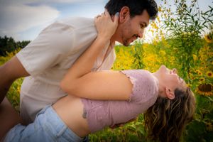 Romantic outdoor photoshoot with couple posing in field of yellow flowers.
