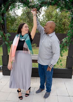 Dancing couple shares joyful moments on a patio surrounded by greenery.