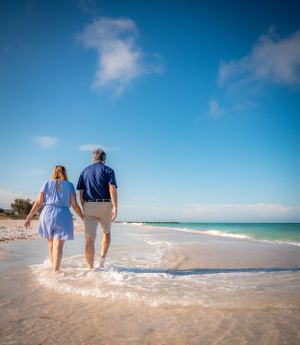 Couple walks together along pristine white sand beach with blue ocean waters.