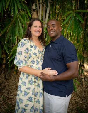 Couple embraces in lush tropical garden setting with bamboo plants.