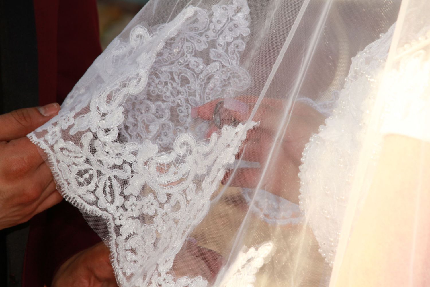 Close-up detail of delicate white lace embellishments on a wedding dress.