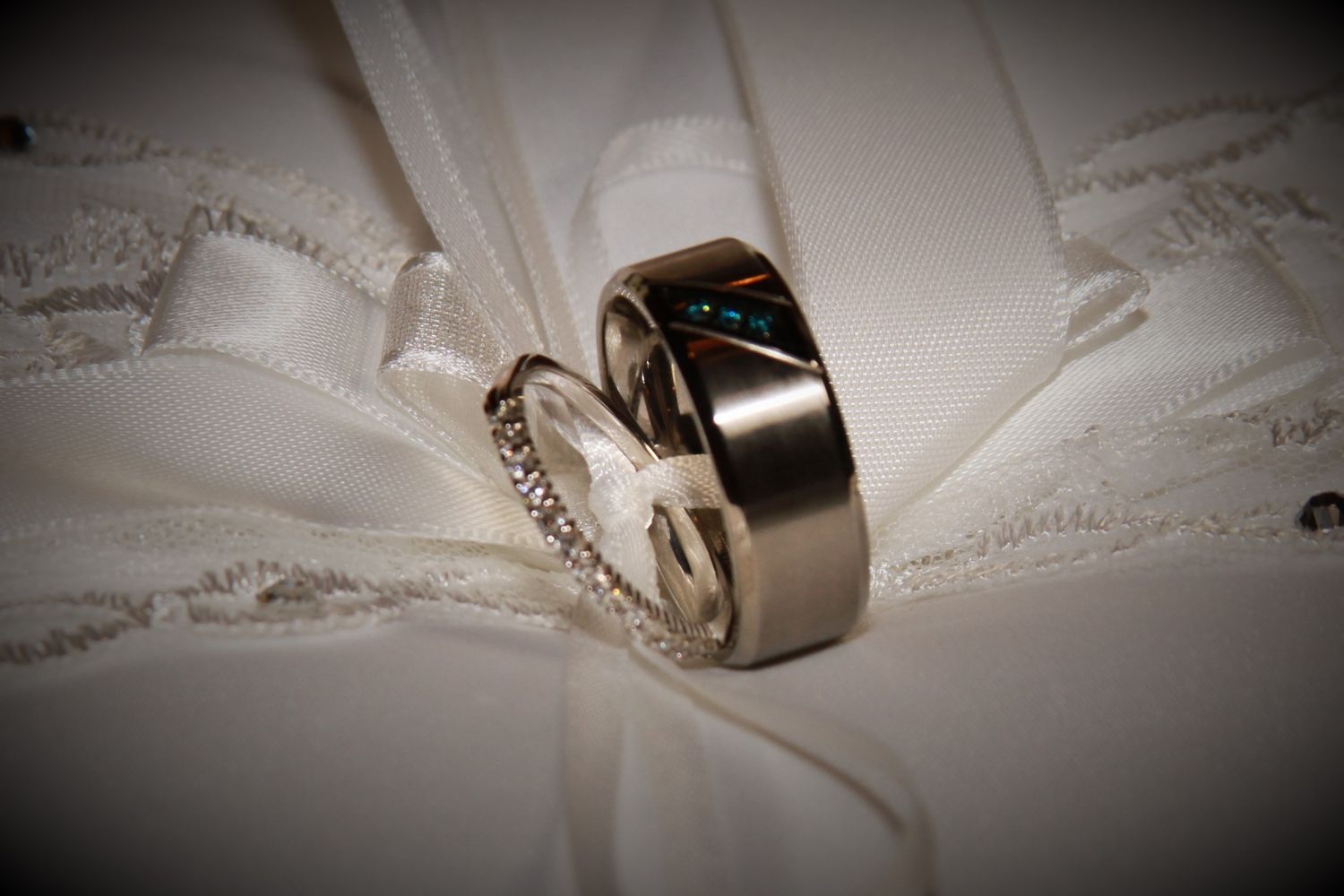 Wedding rings placed artistically on white lace fabric with vignette effect.