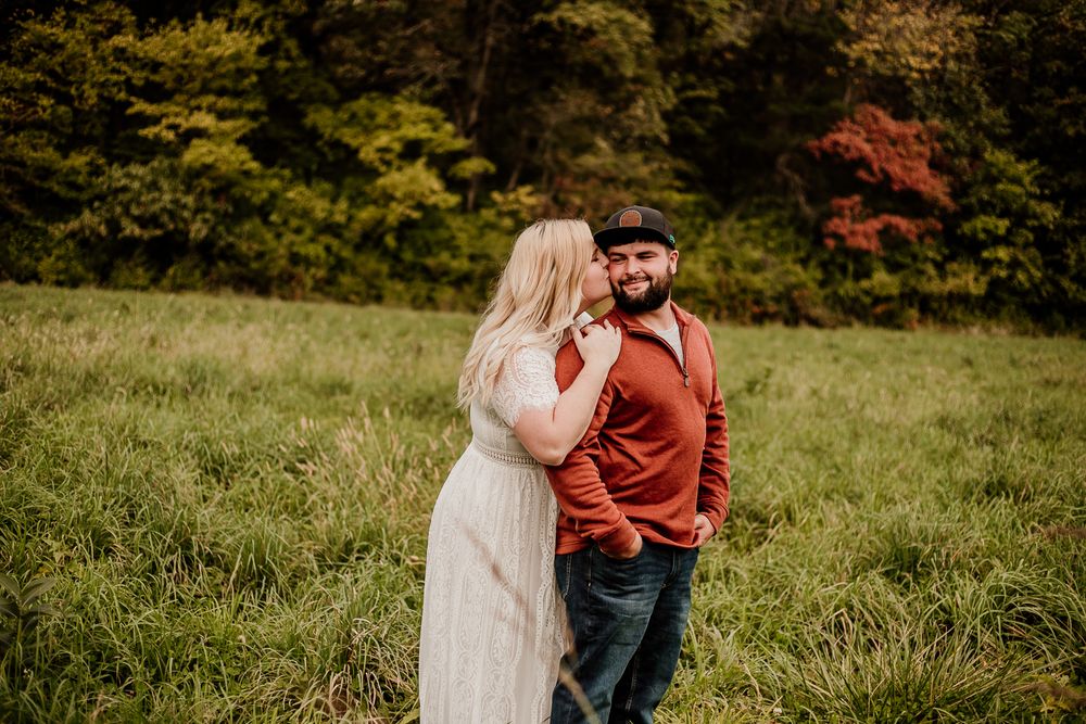 Couple sharing tender moments in a field during golden hour photo session.