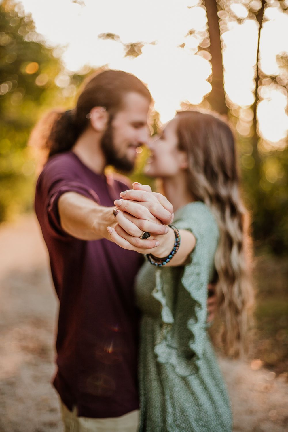 A couple dancing together on a sunlit forest path during golden hour.