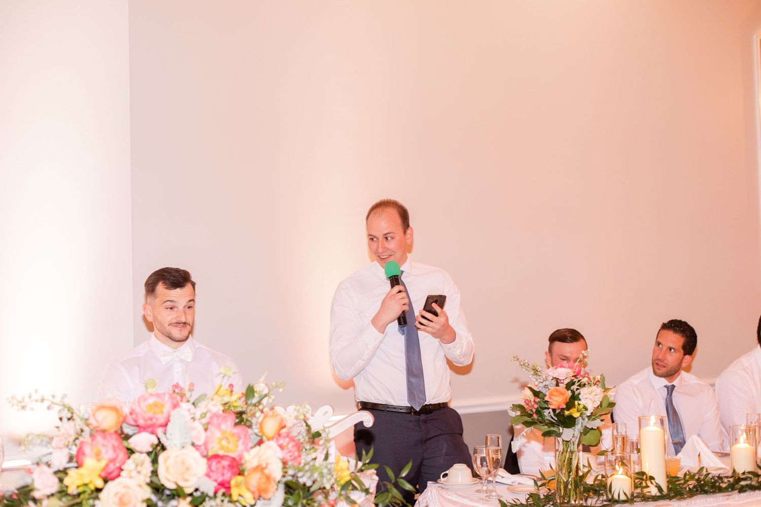 Wedding reception venue with pink and white floral arrangements on elegant dining tables.