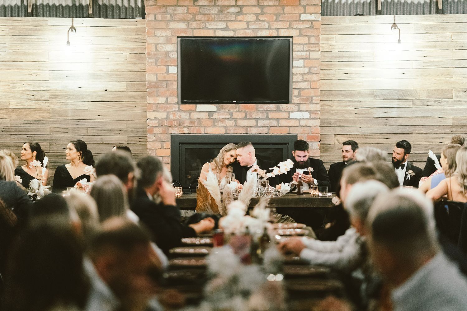 Wedding reception dinner in industrial venue with exposed brick walls and modern decor.