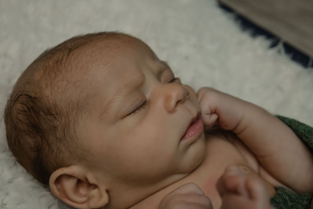 Close-up portrait of peaceful sleeping newborn with hand near face.