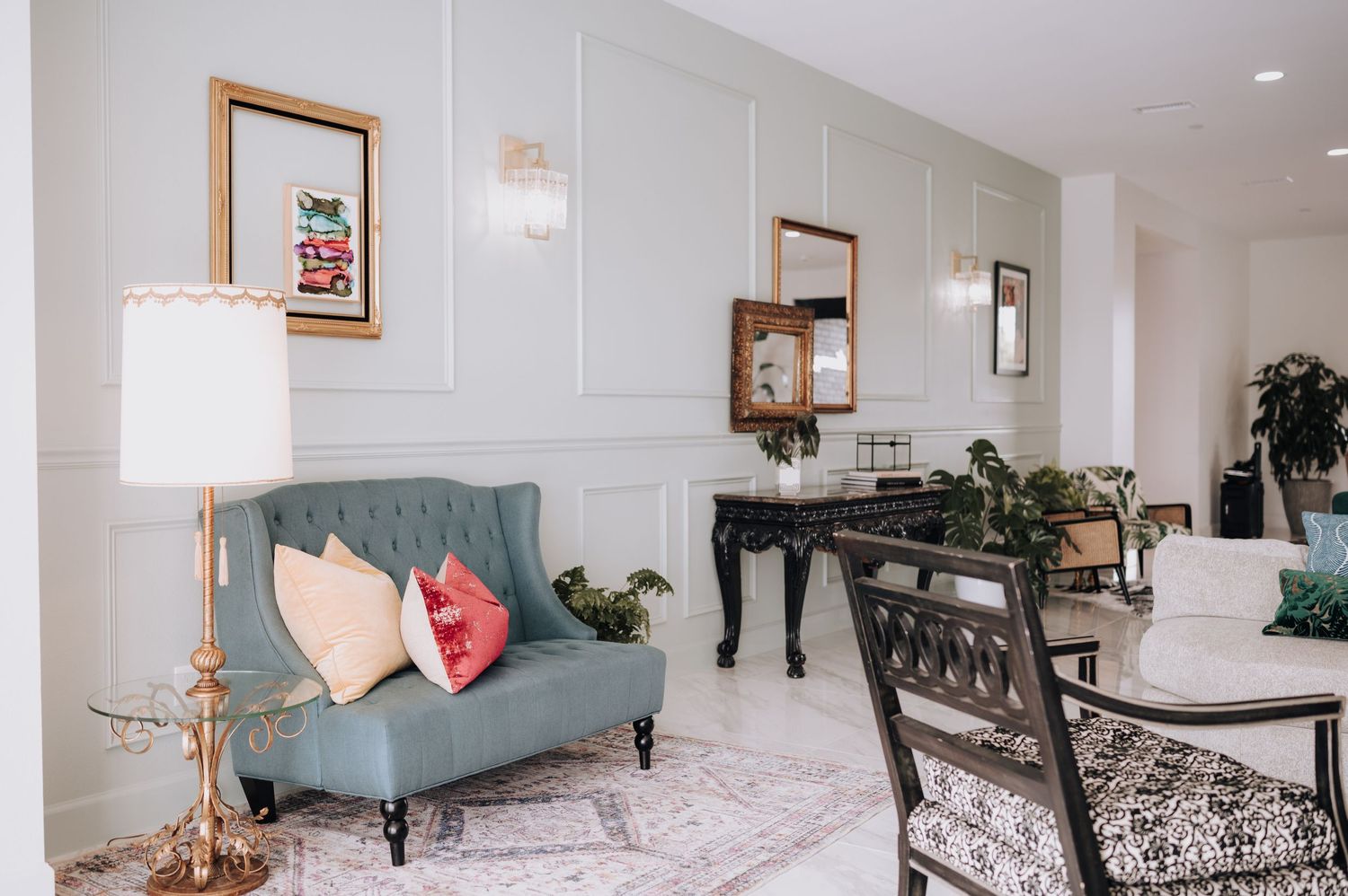 Modern salon waiting area with blue couch, decorative lamp, and elegant interior design.