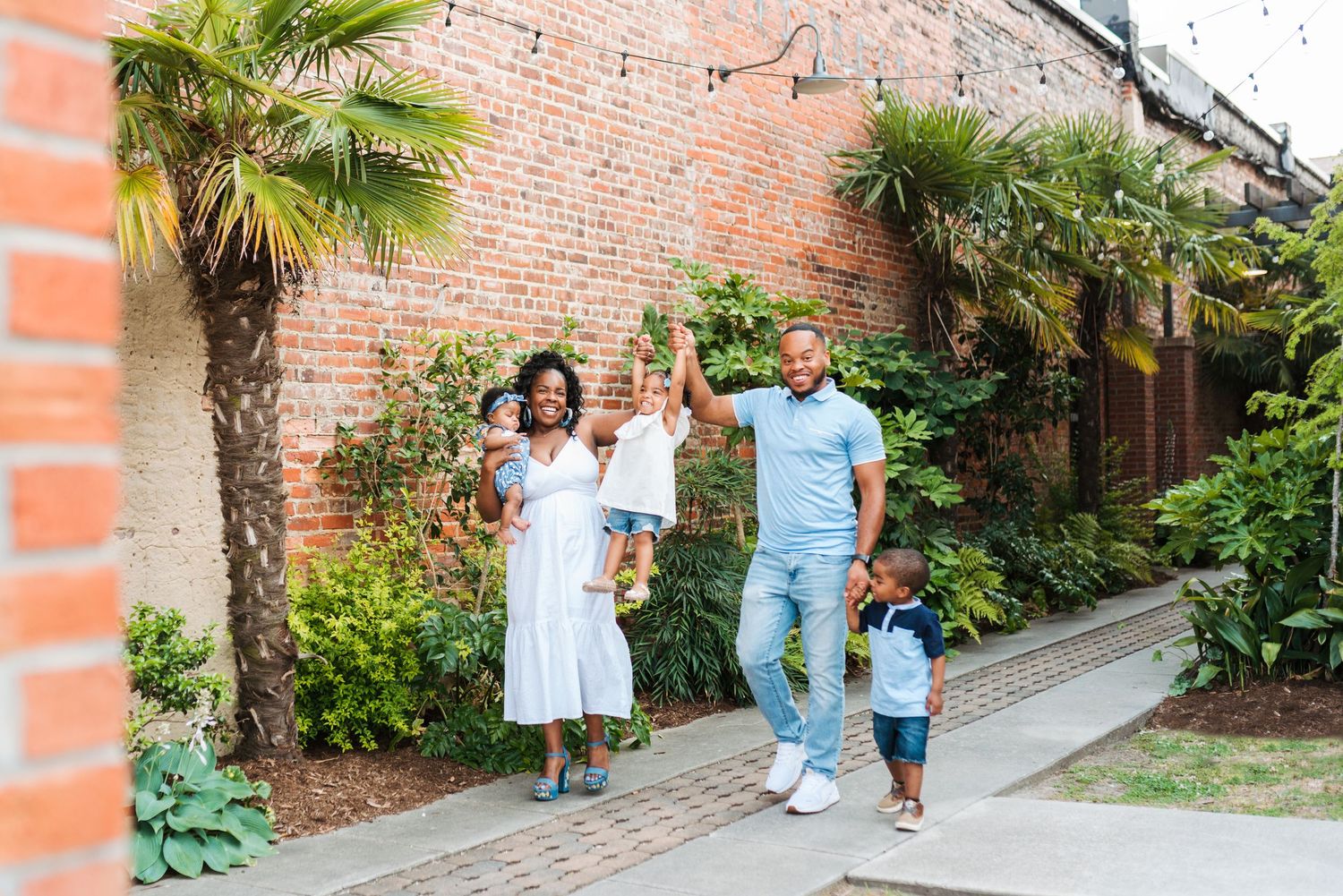 A family walks together along a brick pathway with palm trees.