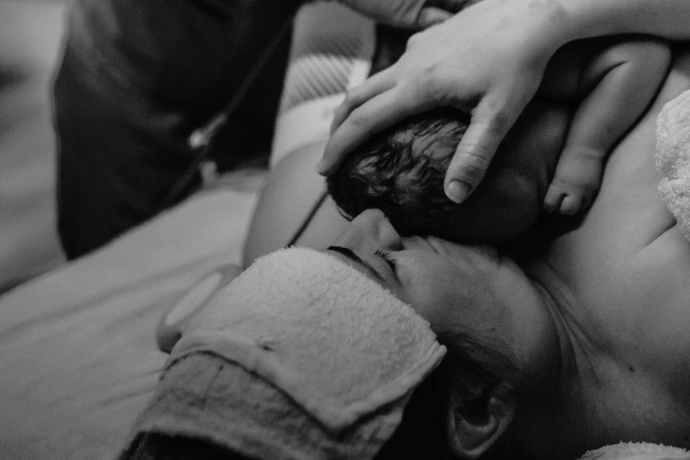 Black and white close-up of a mama holding her brand new newborn baby boy after birth.