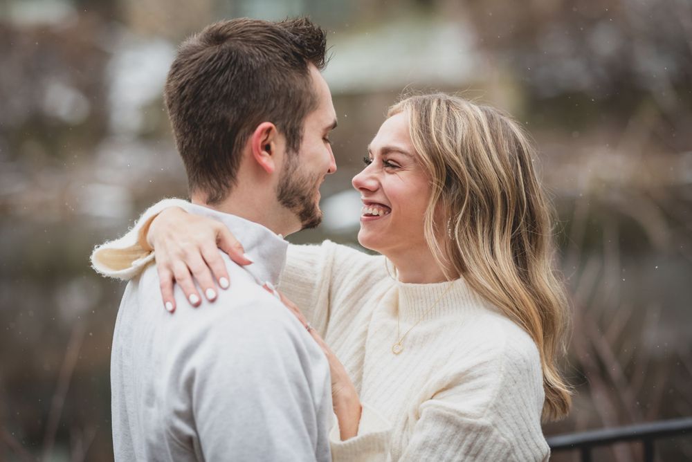 A couple in winter attire sharing joyful moments during their engagement shoot.