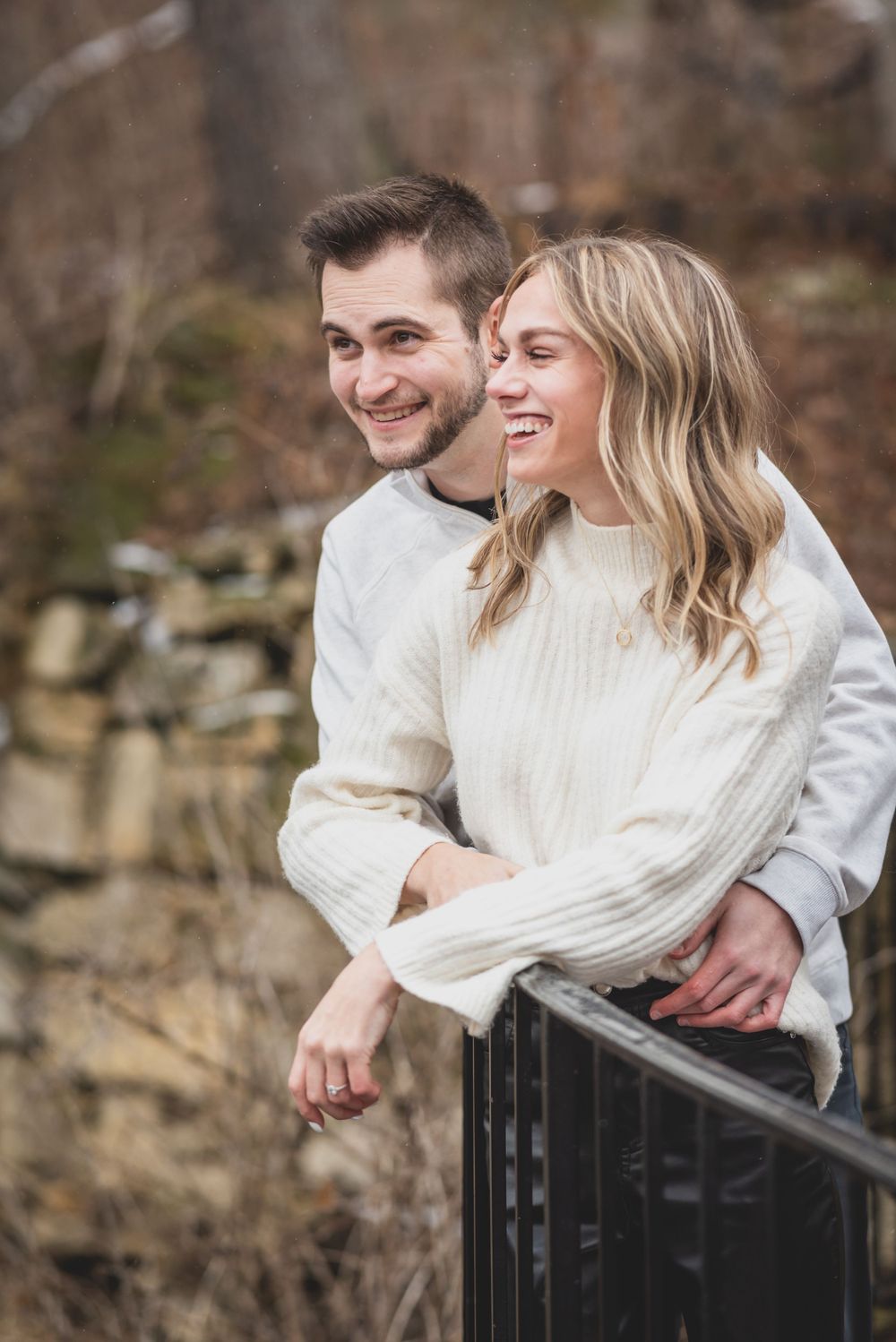 A couple sharing tender moments by an iron railing during their winter photoshoot.