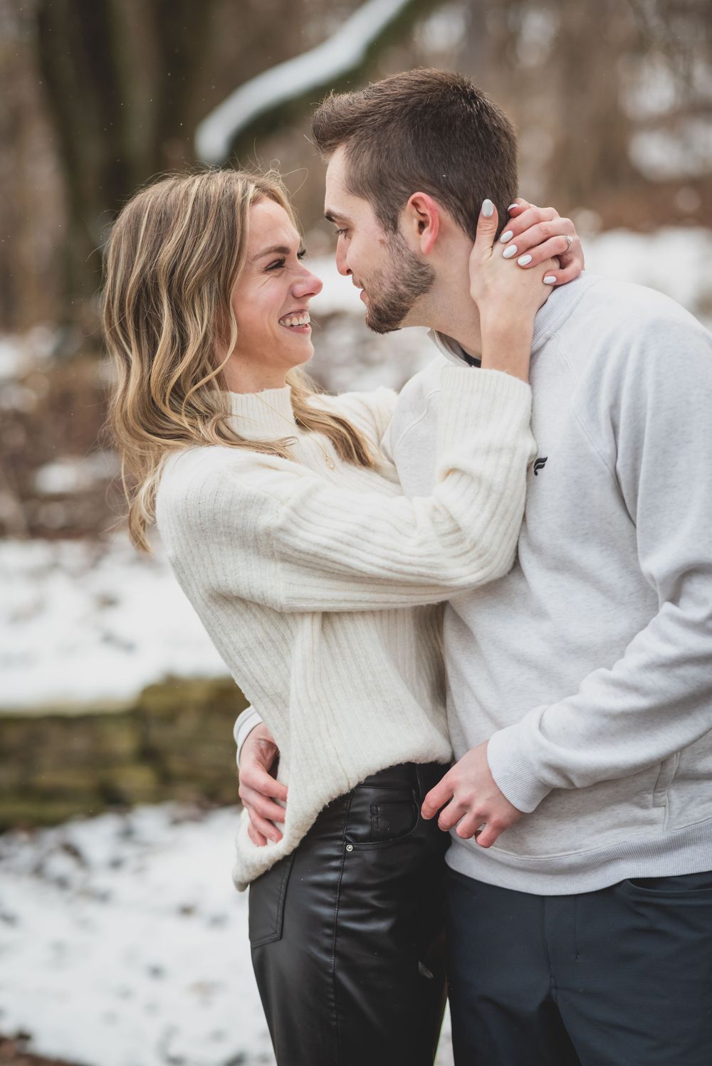 A couple in matching white sweaters sharing intimate moments in a snowy setting.