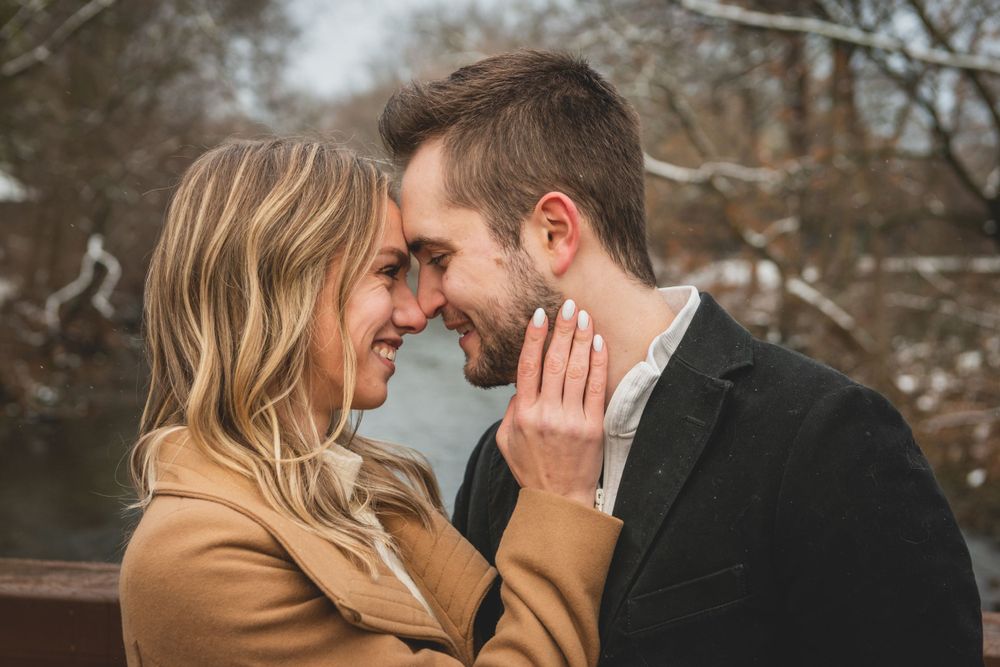 An intimate moment between a couple touching foreheads on a bridge in winter.