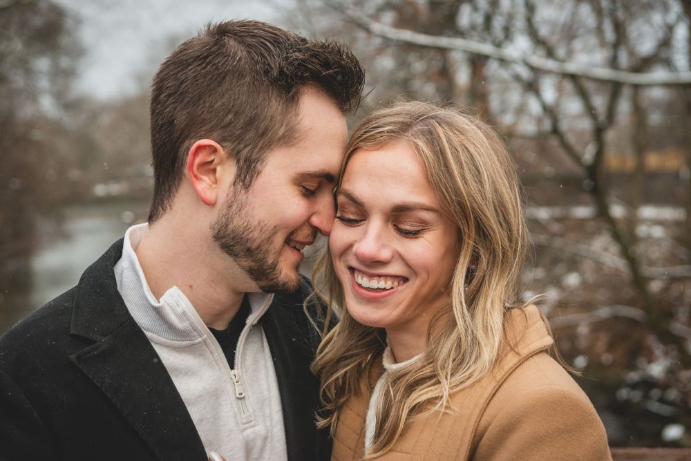 A tender moment captured between a couple in winter clothing sharing laughter outdoors.