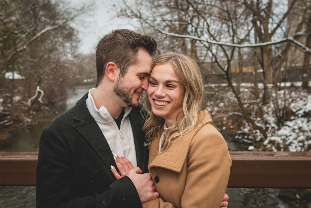 A couple shares an intimate winter moment on a wooden bridge during their photoshoot.
