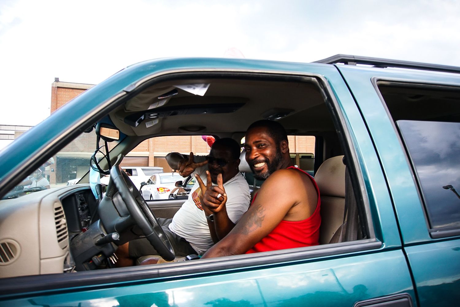 People sitting in turquoise pickup truck during outdoor celebration.