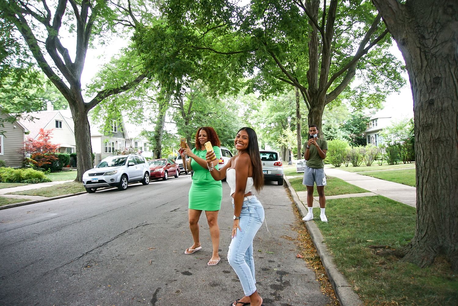 Two people walking and celebrating on a tree-lined residential street.