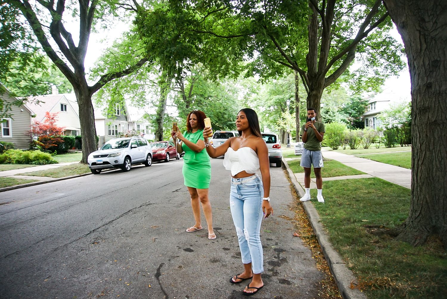 Friends celebrating together on a suburban street lined with mature trees.