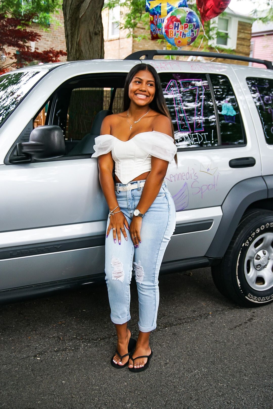 A casual summer celebration scene next to a decorated silver SUV with balloons.