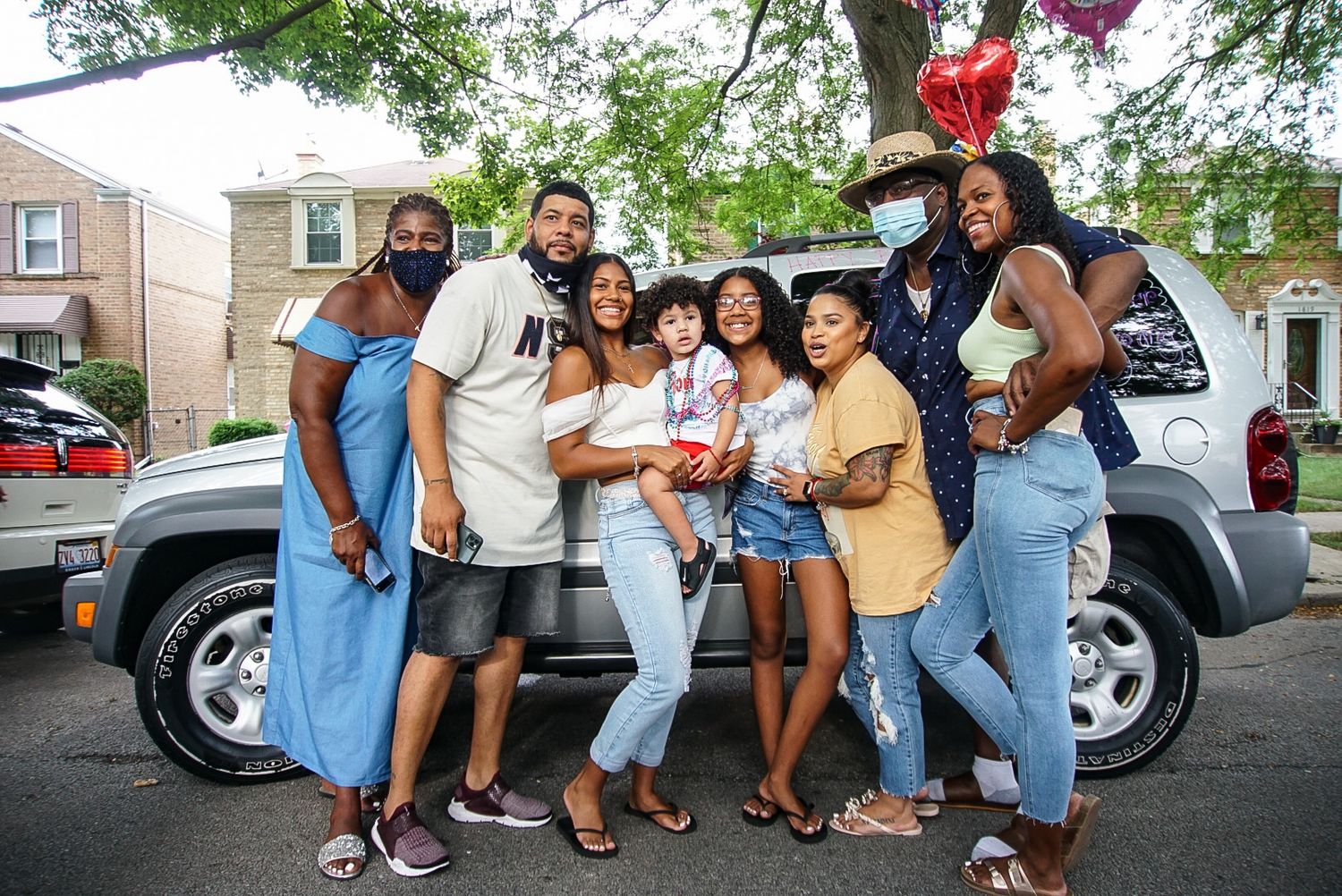 Group of friends celebrating together outside near a parked SUV on a residential street.