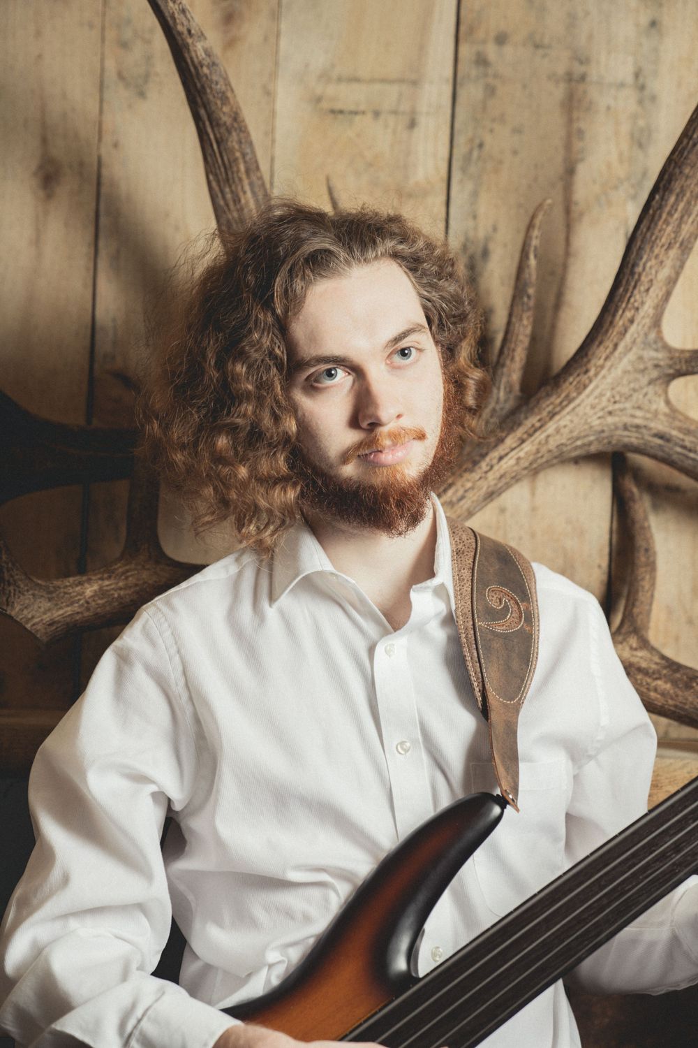 Curly haired guitarist posing in front of antlers