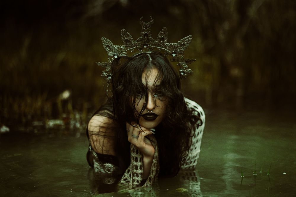Dark fantasy portrait with crown in murky water creating ethereal mood.